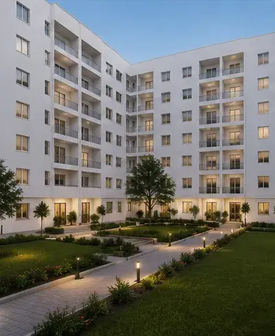 Cour intérieure paysagée en soirée, allées éclairées et façades avec balcons