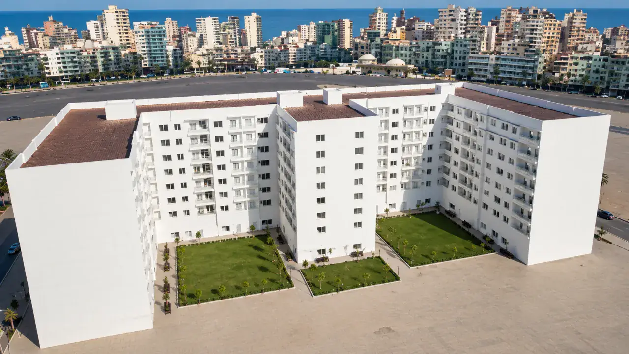 Vue aérienne de la résidence en U et de ses deux jardins intérieurs paysagés, avec les immeubles du centre-ville en arrière-plan